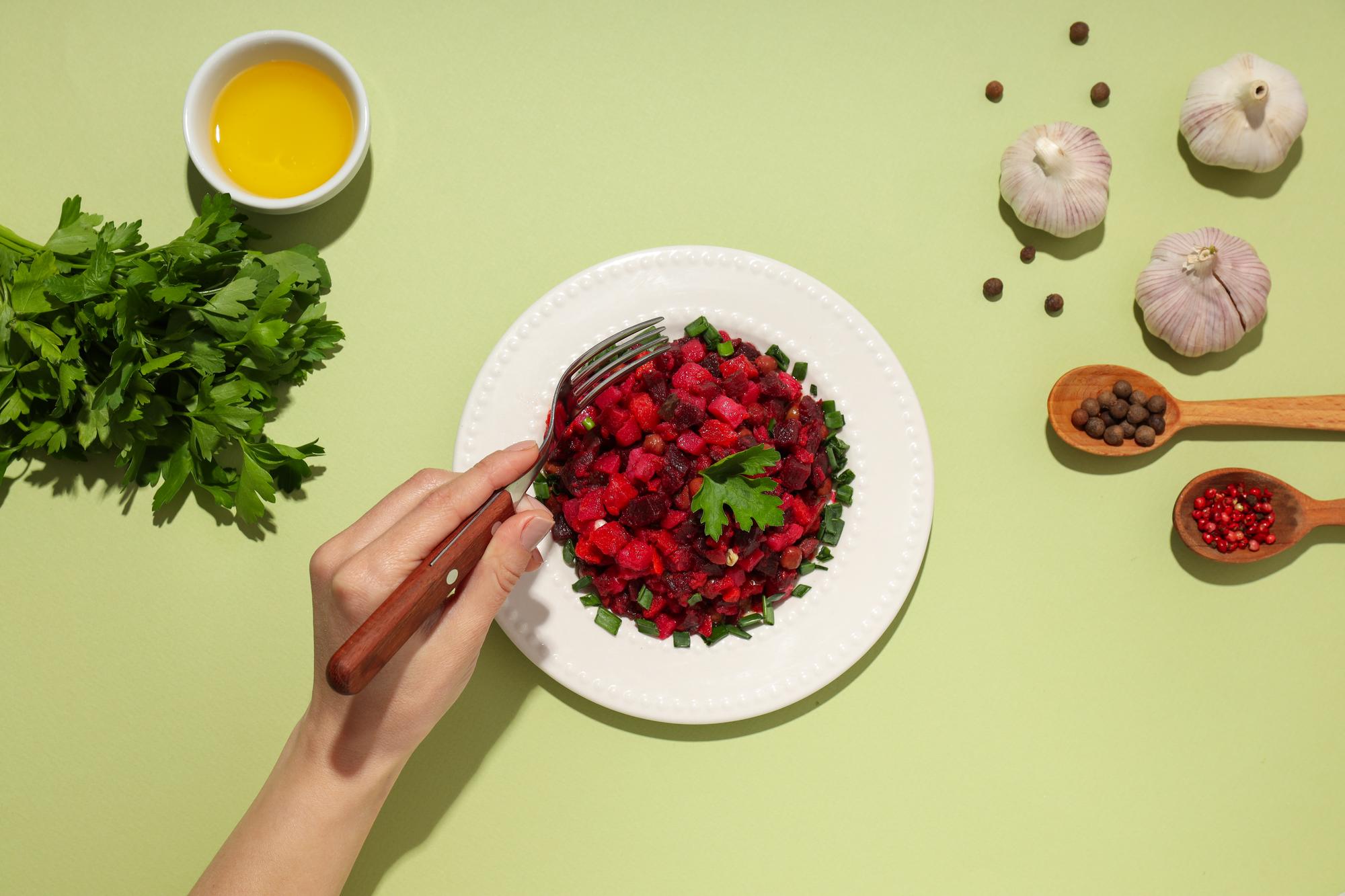 hands plating a composed seasonal dish with herbs and careful technique